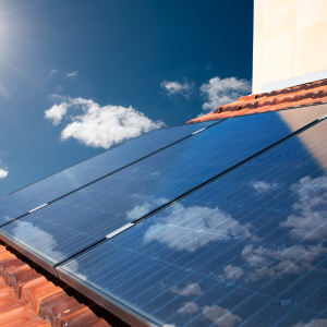 Image of a solar panel mounted an a red tile roof of a residential home.